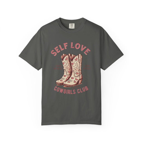 Cream oversized vintage-style t-shirt featuring a graphic of cowgirl boots with pink hearts and the phrase “Self Love Cowgirl Club – I love my body, I love myself.” Western-inspired design with a bold, empowering message.