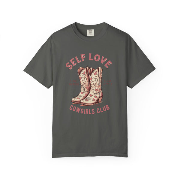 Oversized cream t-shirt featuring a graphic of cowgirl boots with pink hearts and the phrase “Self Love Cowgirl Club – I love my body, I love myself.” Western-themed design with empowering self-love messaging.
