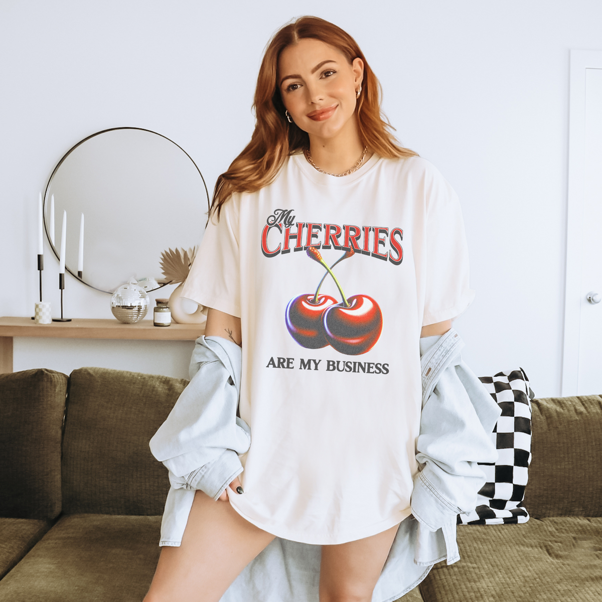 Cream oversized vintage-style t-shirt featuring a bold graphic of two red cherries and the text “My Cherries Are My Business.” A flirty and confident design perfect for making a bold statement.
