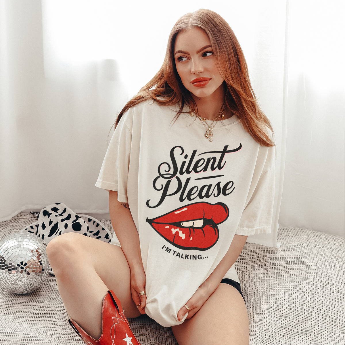 Cream oversized vintage-style t-shirt featuring a bold graphic of glossy red lips and the text “Silent Please I'm Talking...” A sassy and empowering design perfect for confident, bold style.

