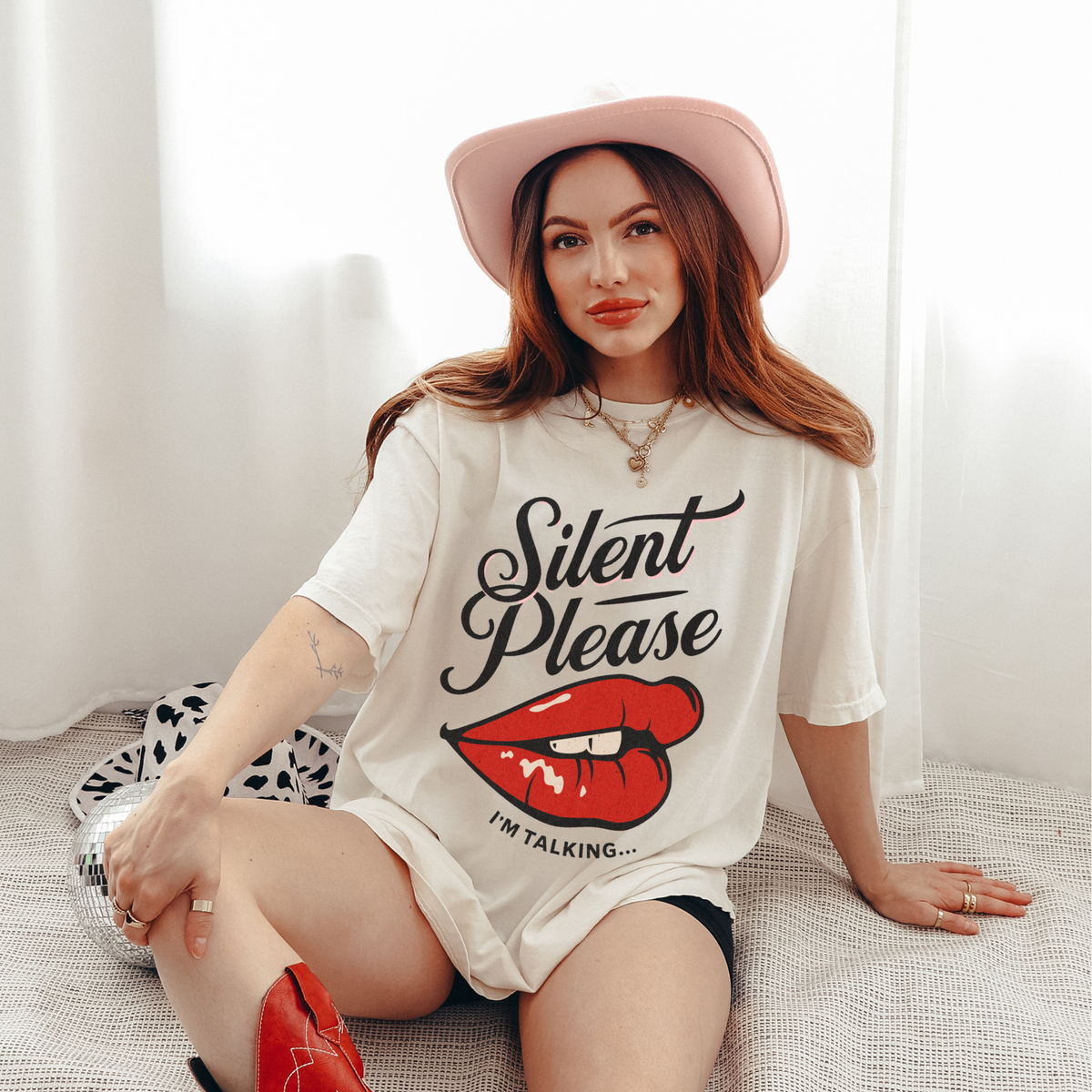 Cream oversized vintage-style t-shirt featuring a bold graphic of glossy red lips and the text “Silent Please I'm Talking...” A sassy and empowering design perfect for confident, bold style.

