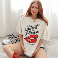 Cream oversized vintage-style t-shirt featuring a bold graphic of glossy red lips and the text “Silent Please I'm Talking...” A sassy and empowering design perfect for confident, bold style.

