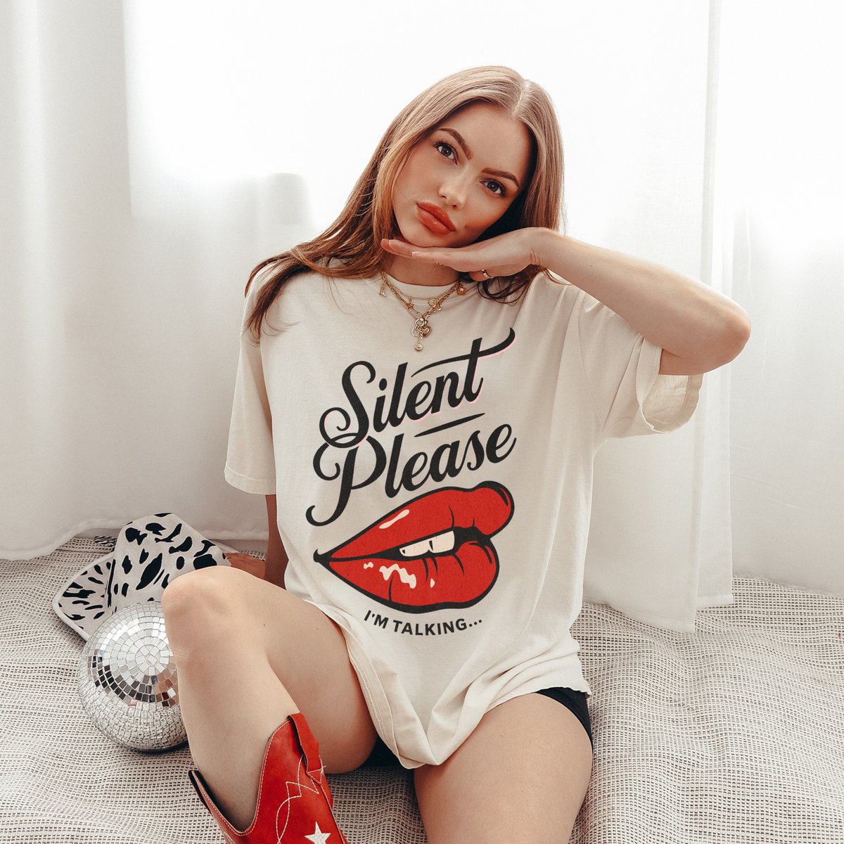Cream oversized vintage-style t-shirt featuring a bold graphic of glossy red lips and the text “Silent Please I'm Talking...” A sassy and empowering design perfect for confident, bold style.


