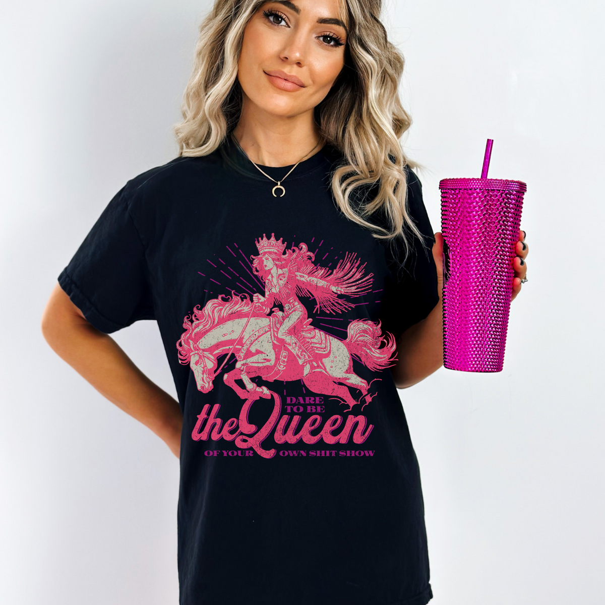 Model wearing an oversized ‘Dare to Be the Queen of Your Own Sh*t Show’ T-Shirt with bold western-style graphic. Soft, vintage-washed cotton styled with confident, chaotic queen energy.


